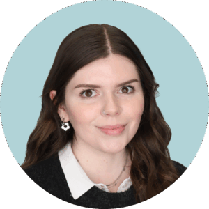 A professional portrait of a young woman with dark long hair against a pale blue background